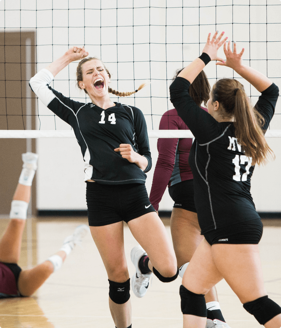 2 female volleyball players celebrate after a won point.