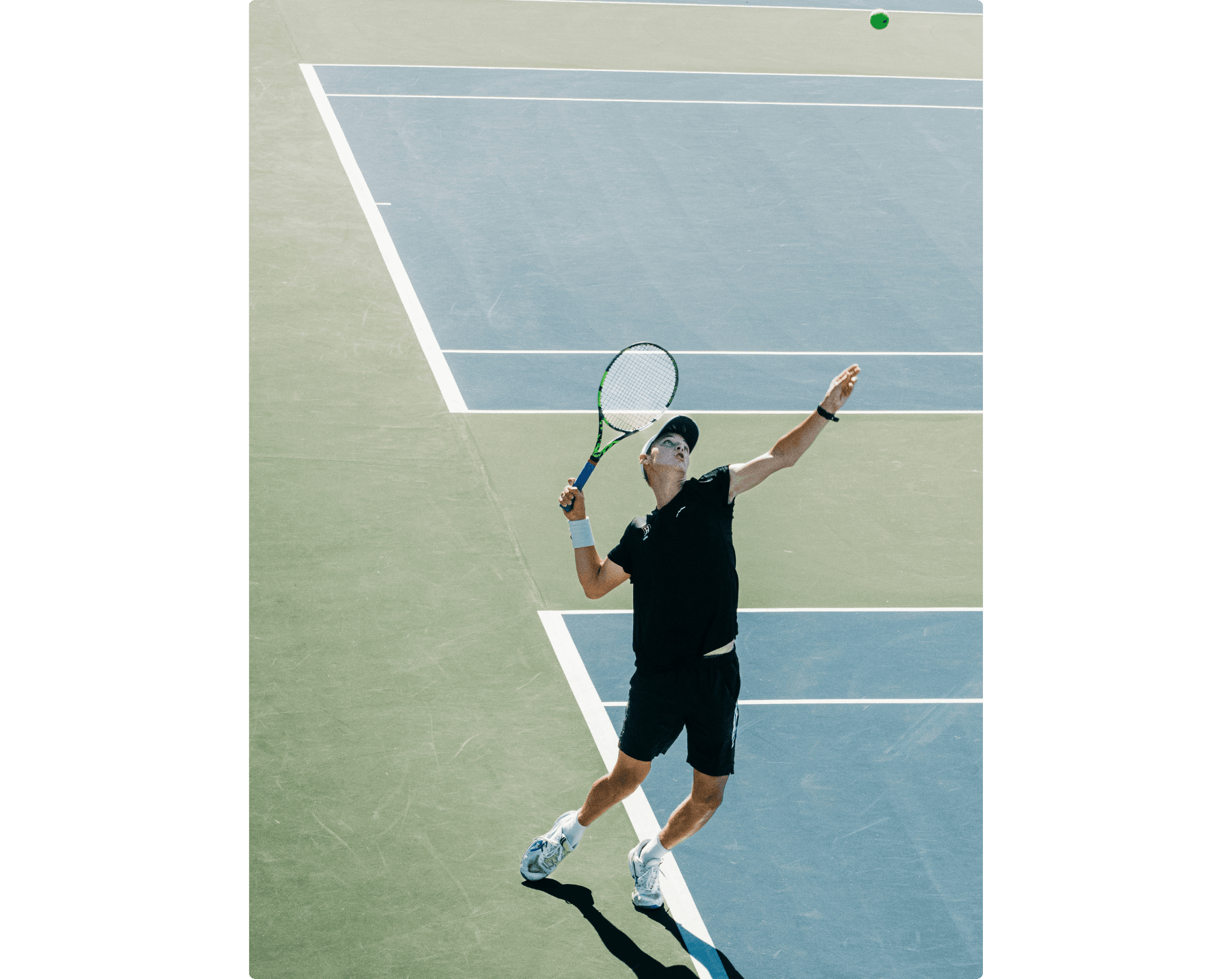 The athlete is in the final motion, before jumpig off the ground to hit the tennis ball. A tennis player on hardcourt is about to hit a serve.