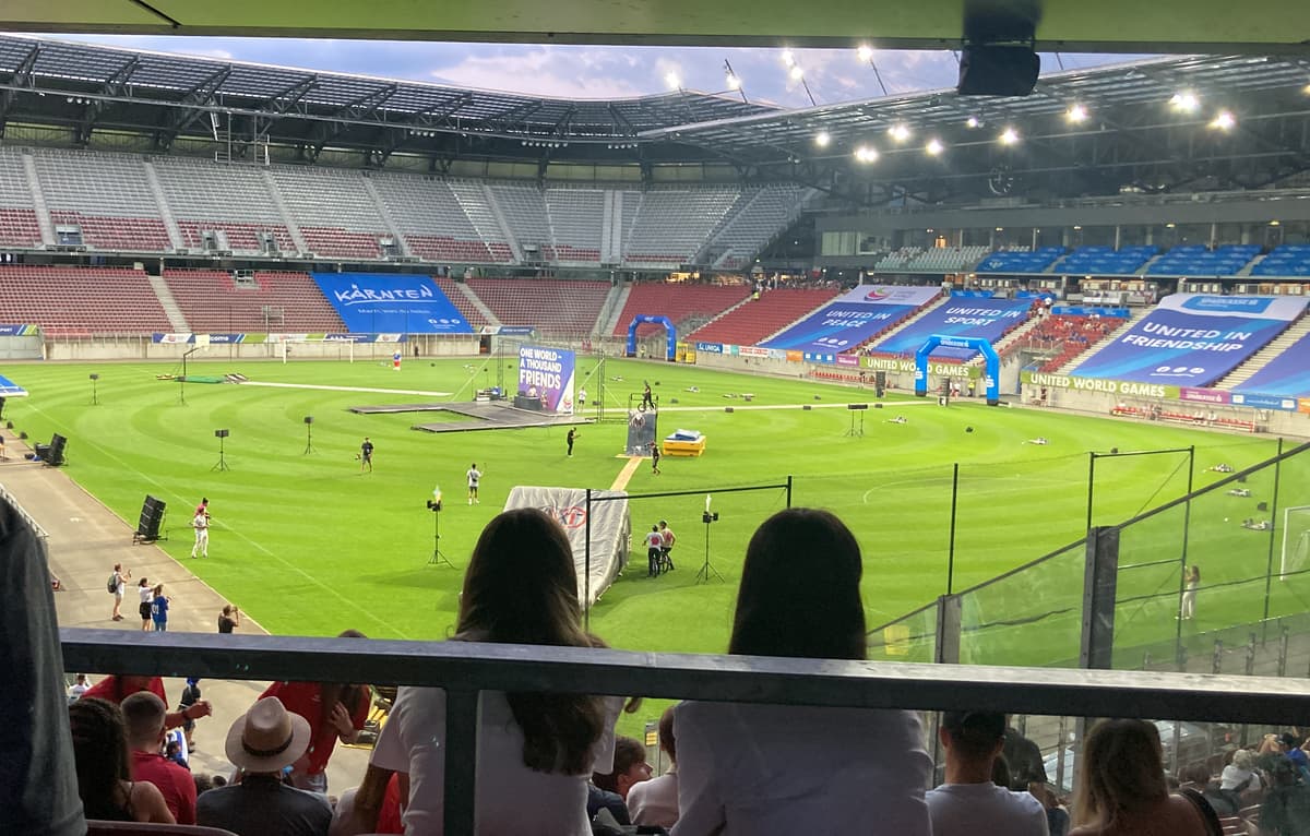 Wörthersee Stadium during United World Games View from the stands of the Wörthersee Stadium in Klagenfurt during the United World Games, featuring a large soccer field with event banners.